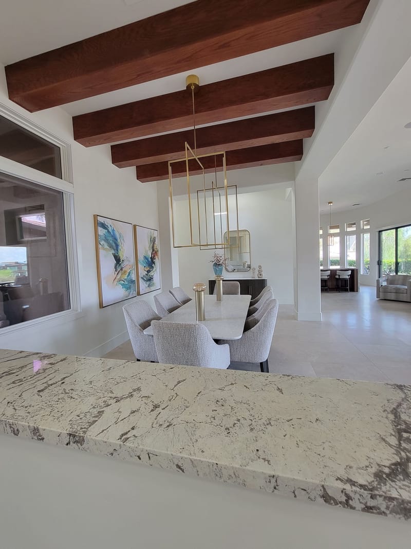 Open-concept dining area with white painted walls and wood beams