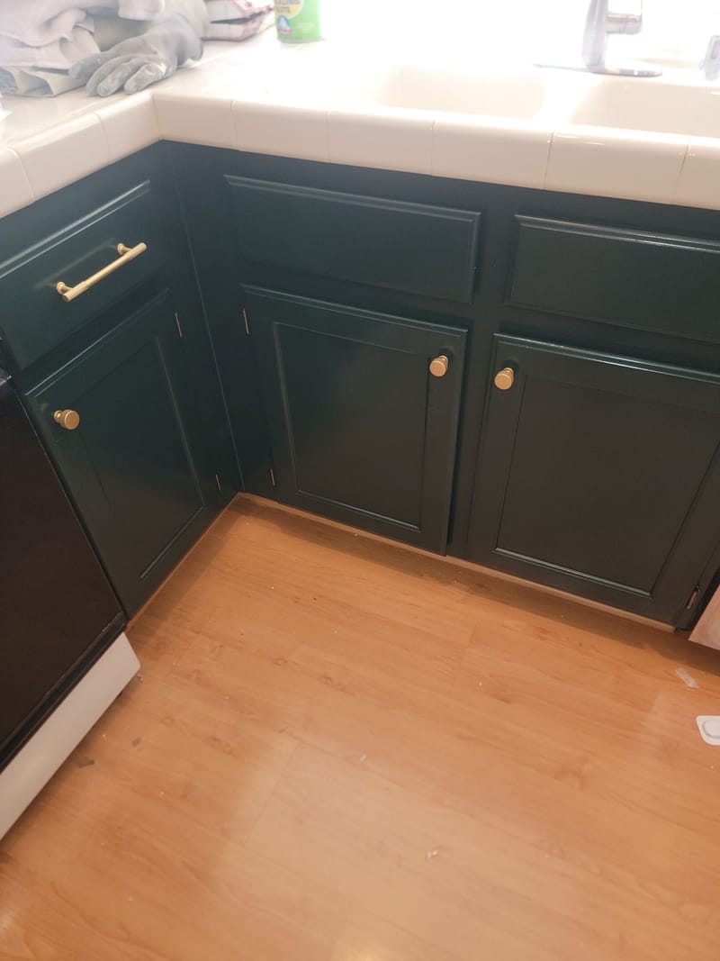 Kitchen cabinets painted dark emerald green with gold hardware