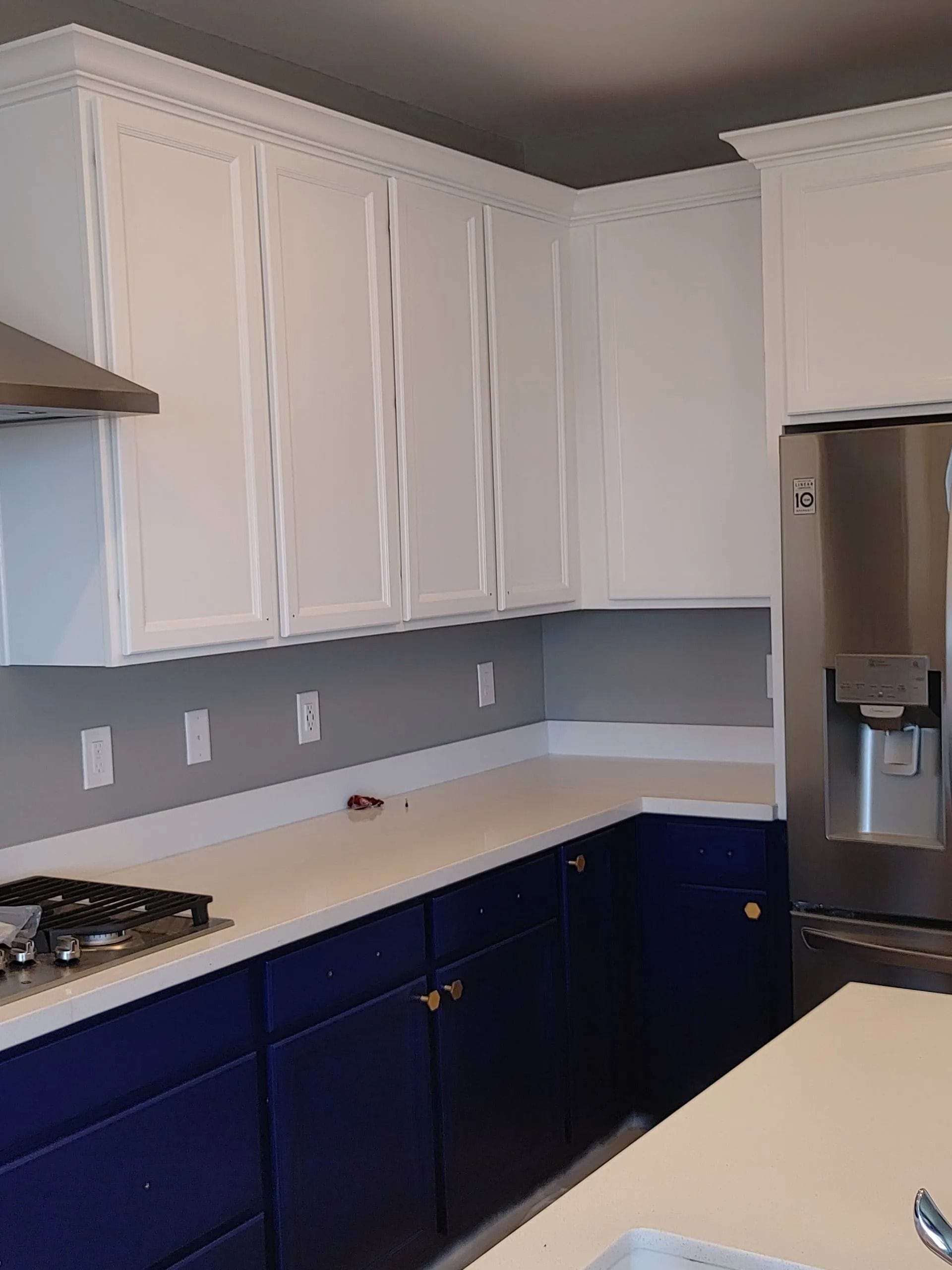 Kitchen with white upper cabinets, navy blue lower cabinets, and a white countertop.