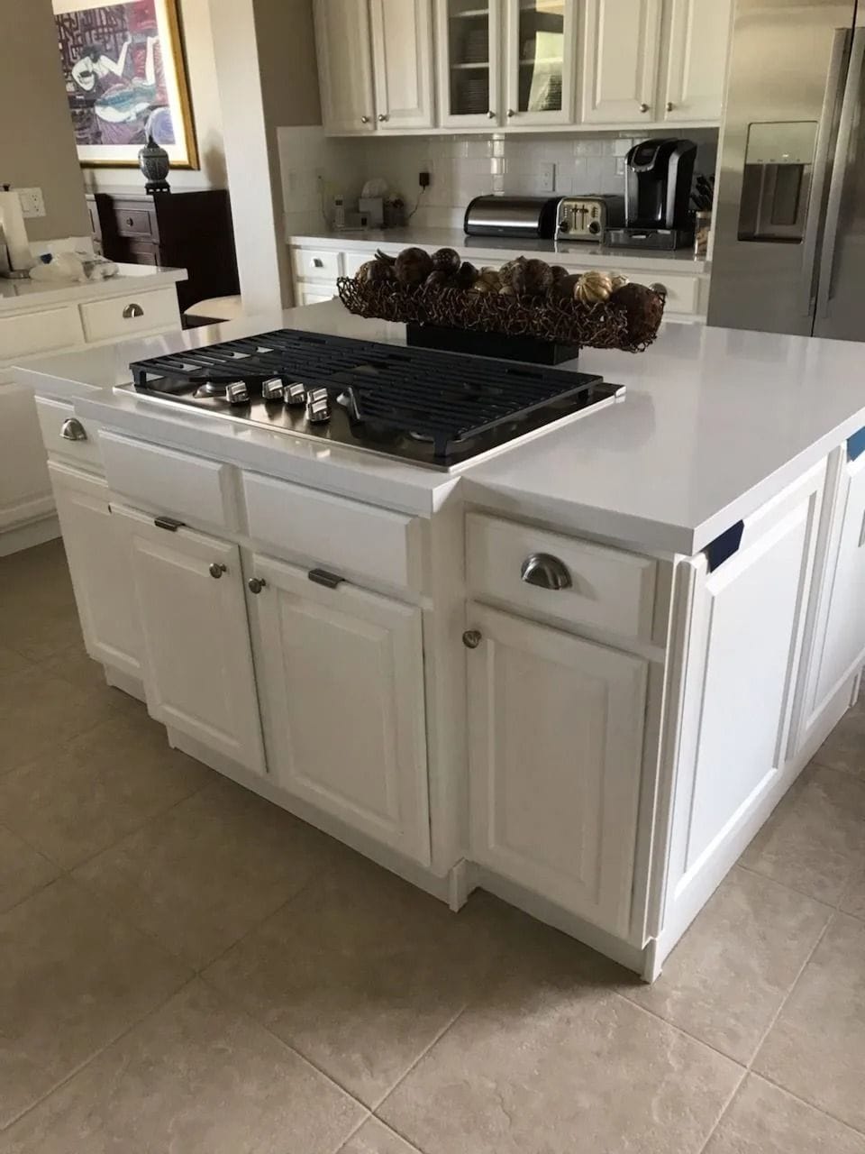 White kitchen island with gas cooktop, cabinets, and countertop.