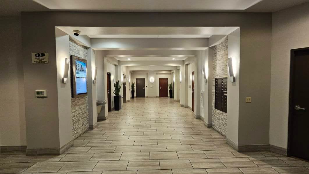 Long hallway with doors, wall lights, and textured walls.